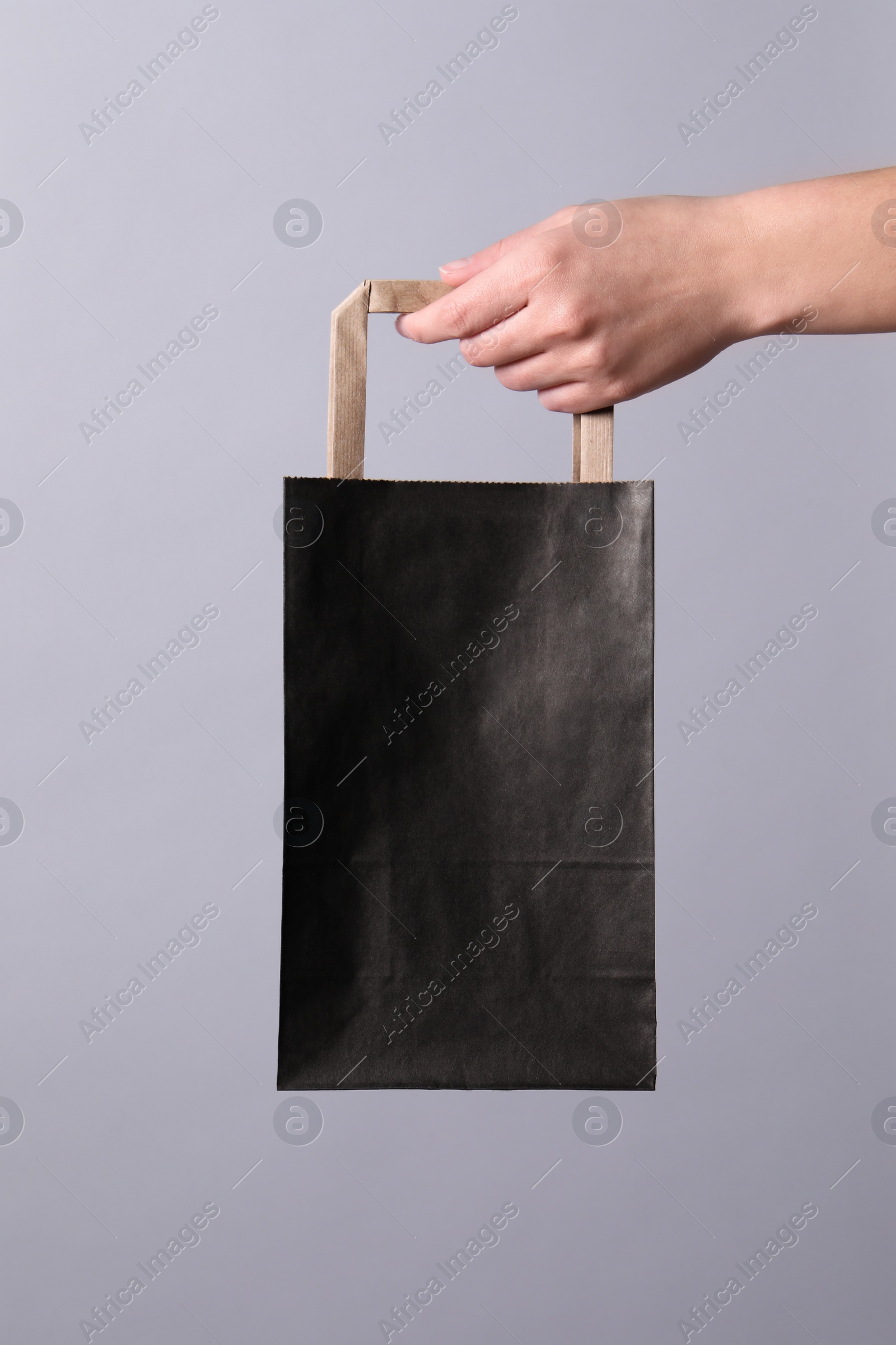 Photo of Woman holding paper shopping bag on grey background, closeup