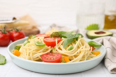 Photo of Plate of delicious pasta primavera and ingredients on white table, closeup