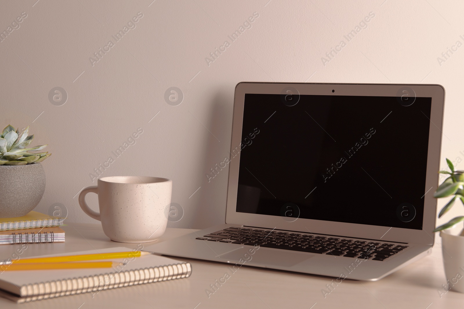 Photo of Modern laptop cup and notebooks on white table