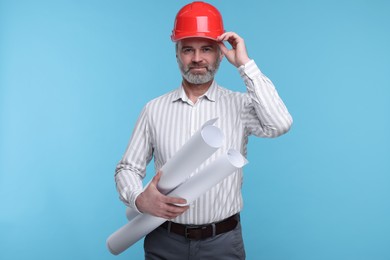 Photo of Architect in hard hat holding drafts on light blue background