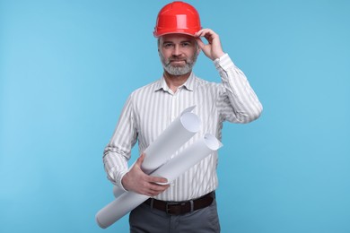 Architect in hard hat holding drafts on light blue background