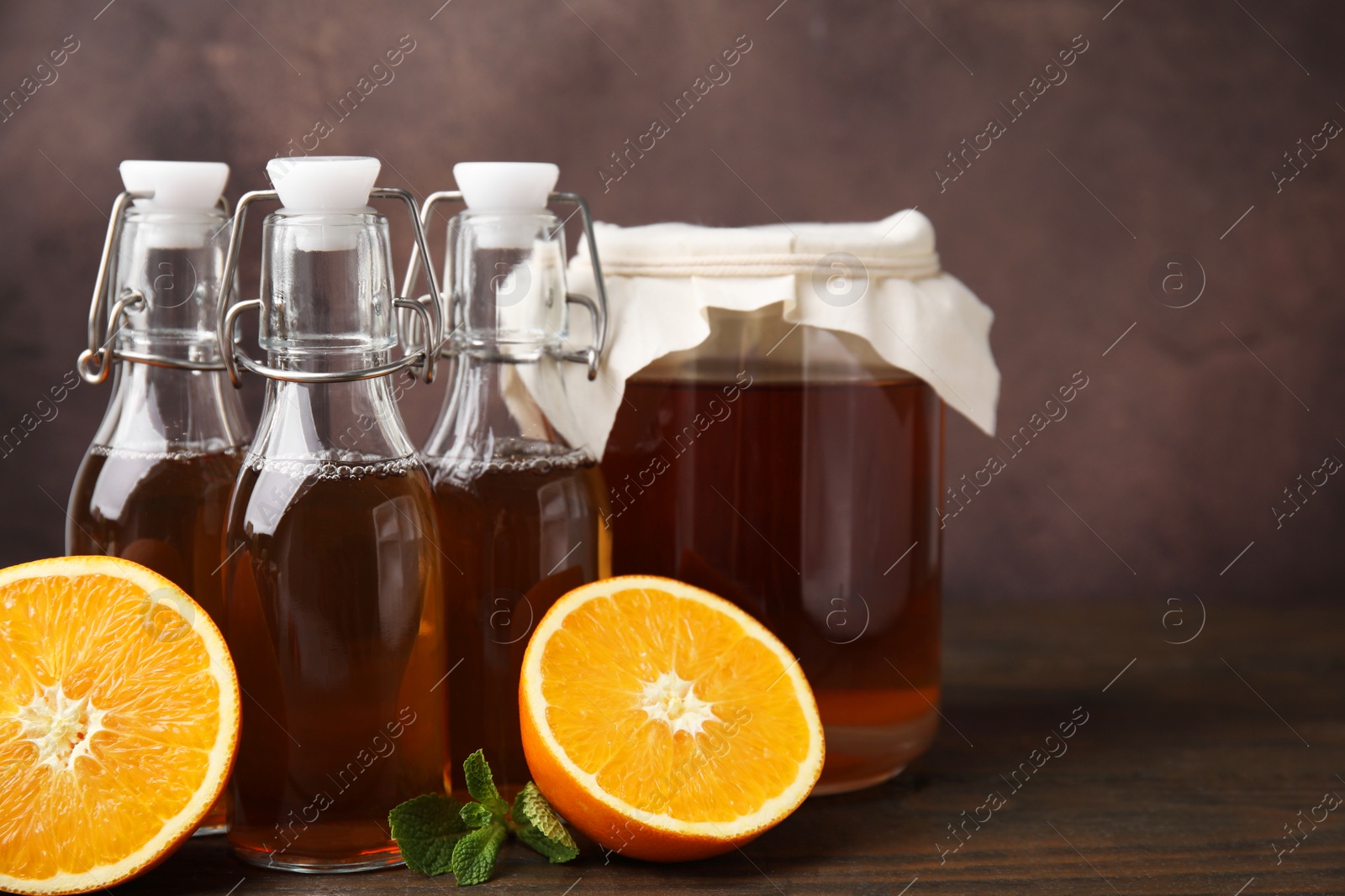 Photo of Tasty kombucha, mint and orange on wooden table