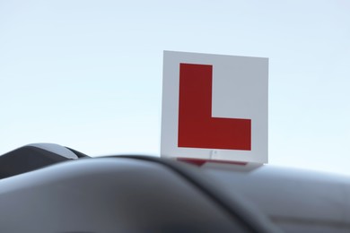 Photo of L-plate on car outdoors, space for text. Driving school