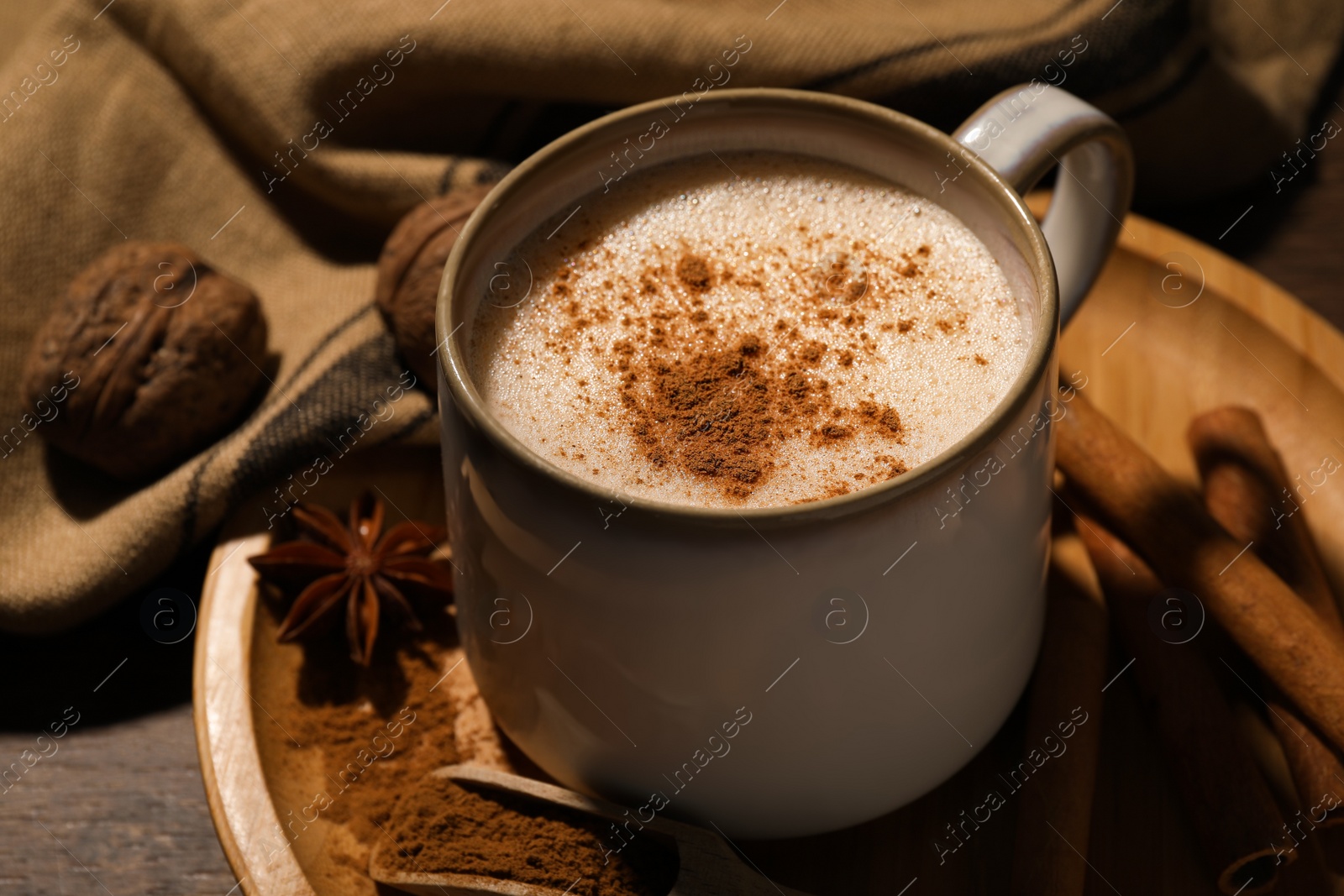 Photo of Cup of delicious eggnog with spices on wooden table