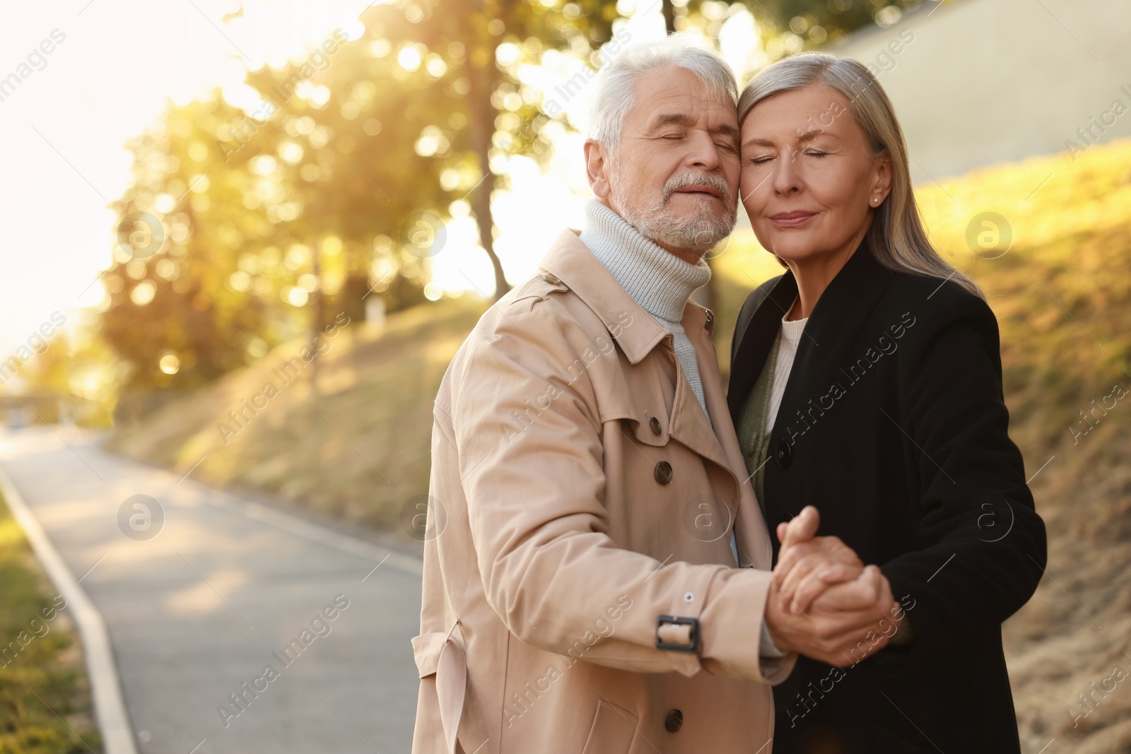 Photo of Affectionate senior couple dancing together outdoors, space for text