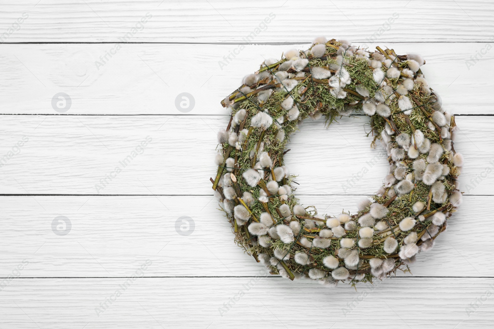 Photo of Wreath made of beautiful willow flowers on white wooden table, top view. Space for text