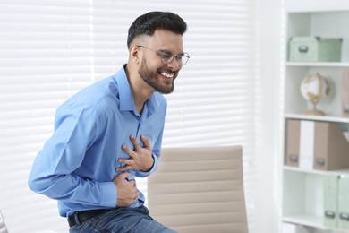 Handsome young man laughing in office, space for text