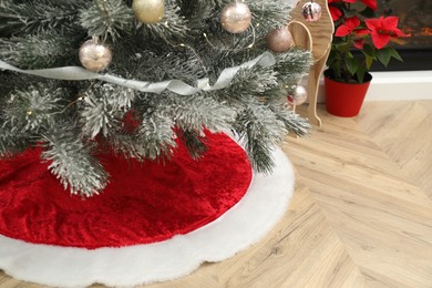 Photo of Beautifully decorated Christmas tree with skirt indoors