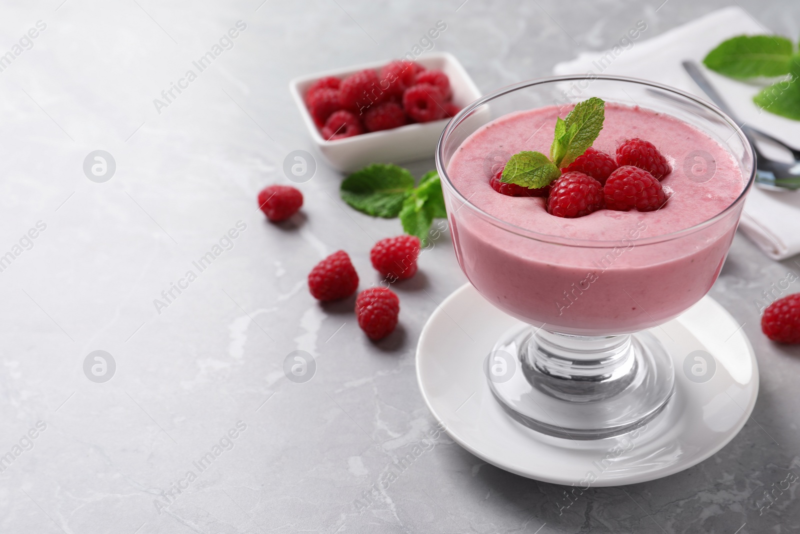 Photo of Delicious raspberry mousse with mint on grey marble table, space for text
