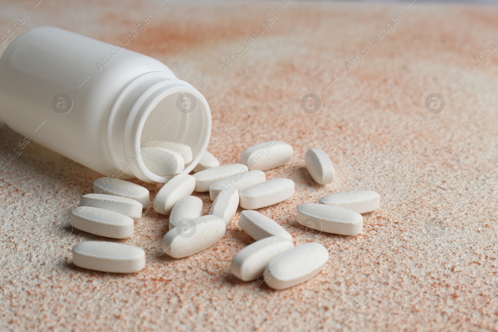 Photo of White medical bottle and pills on color textured surface, closeup. Space for text