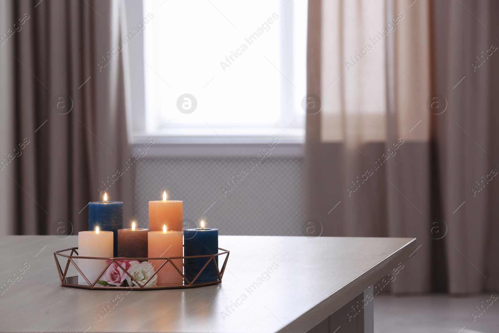Photo of Tray with burning candles and flowers on table indoors. Space for text