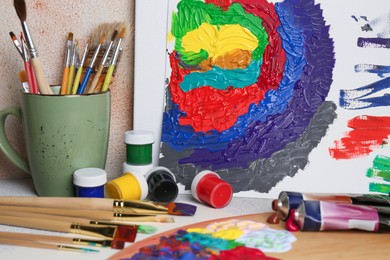 Photo of Abstract colorful painting and different artist's tools on textured table