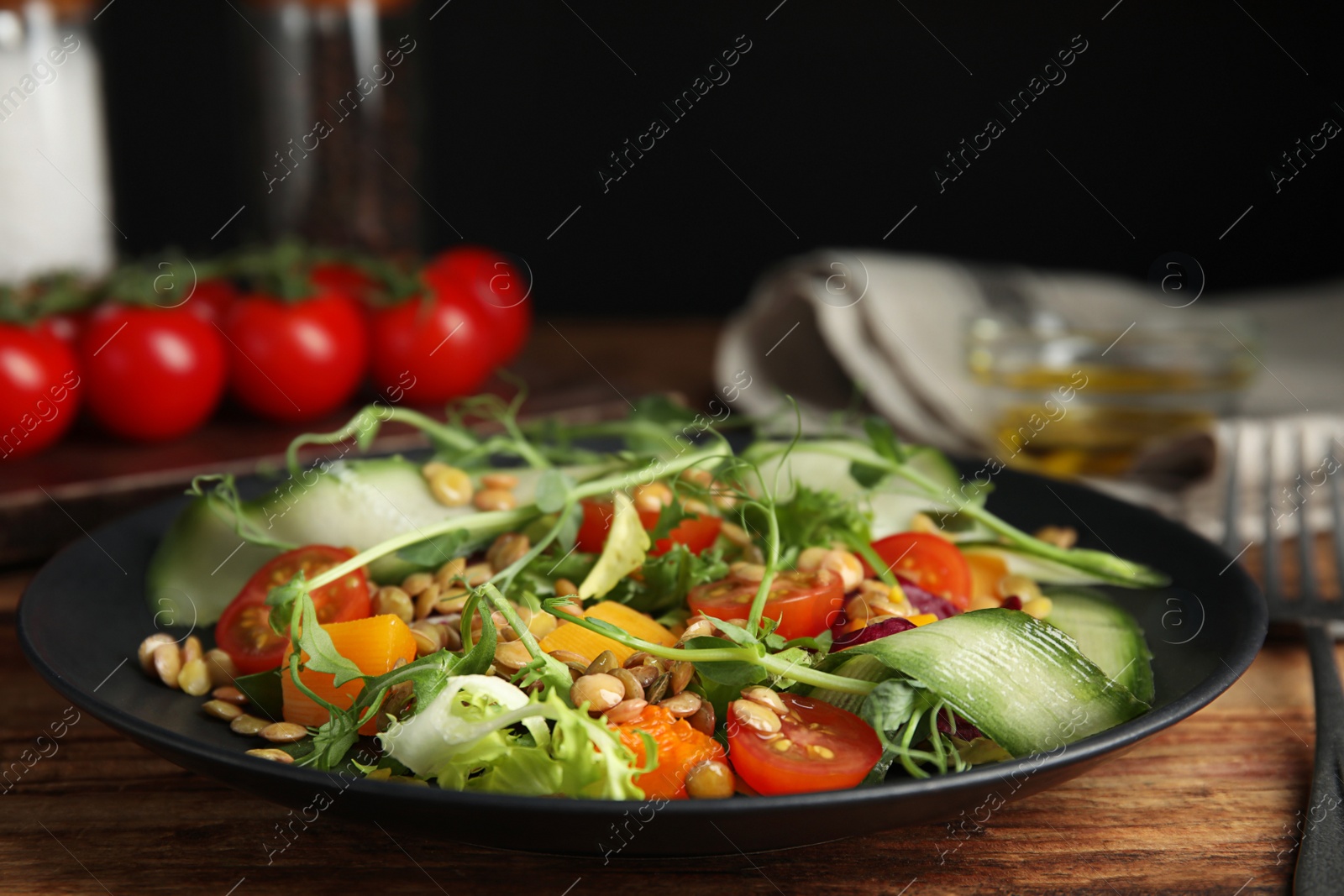Photo of Delicious salad with lentils and vegetables on wooden table