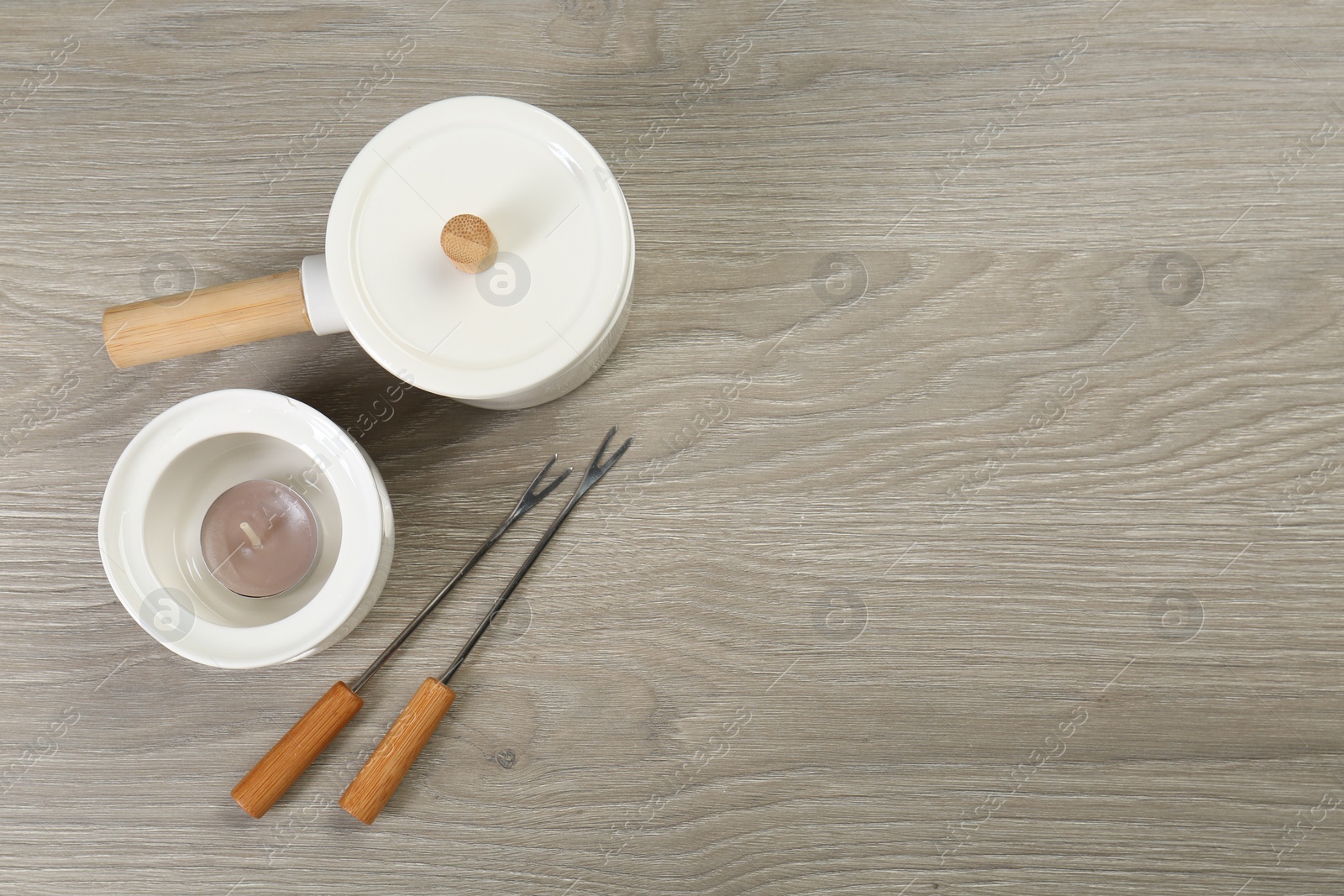 Photo of Fondue set on wooden table, flat lay. Space for text