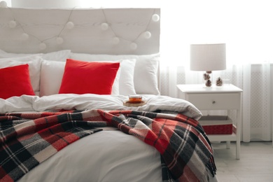 Photo of Comfortable bed with warm checkered plaid in stylish room interior