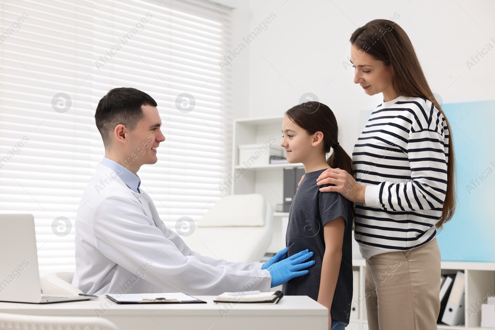 Photo of Gastroenterologist examining girl with stomach ache in clinic