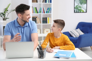 Photo of Dad helping his son with homework in room