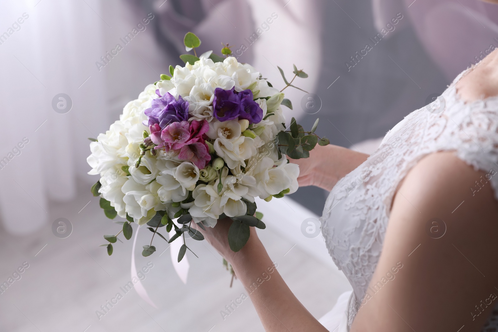 Photo of Bride holding beautiful bouquet with spring freesia flowers, closeup