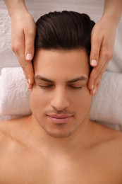 Photo of Man receiving facial massage in beauty salon, top view