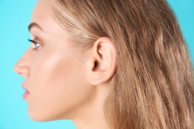 Photo of Young woman on color background, closeup. Hearing problem