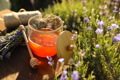 Jar of honey on wooden table in lavender field