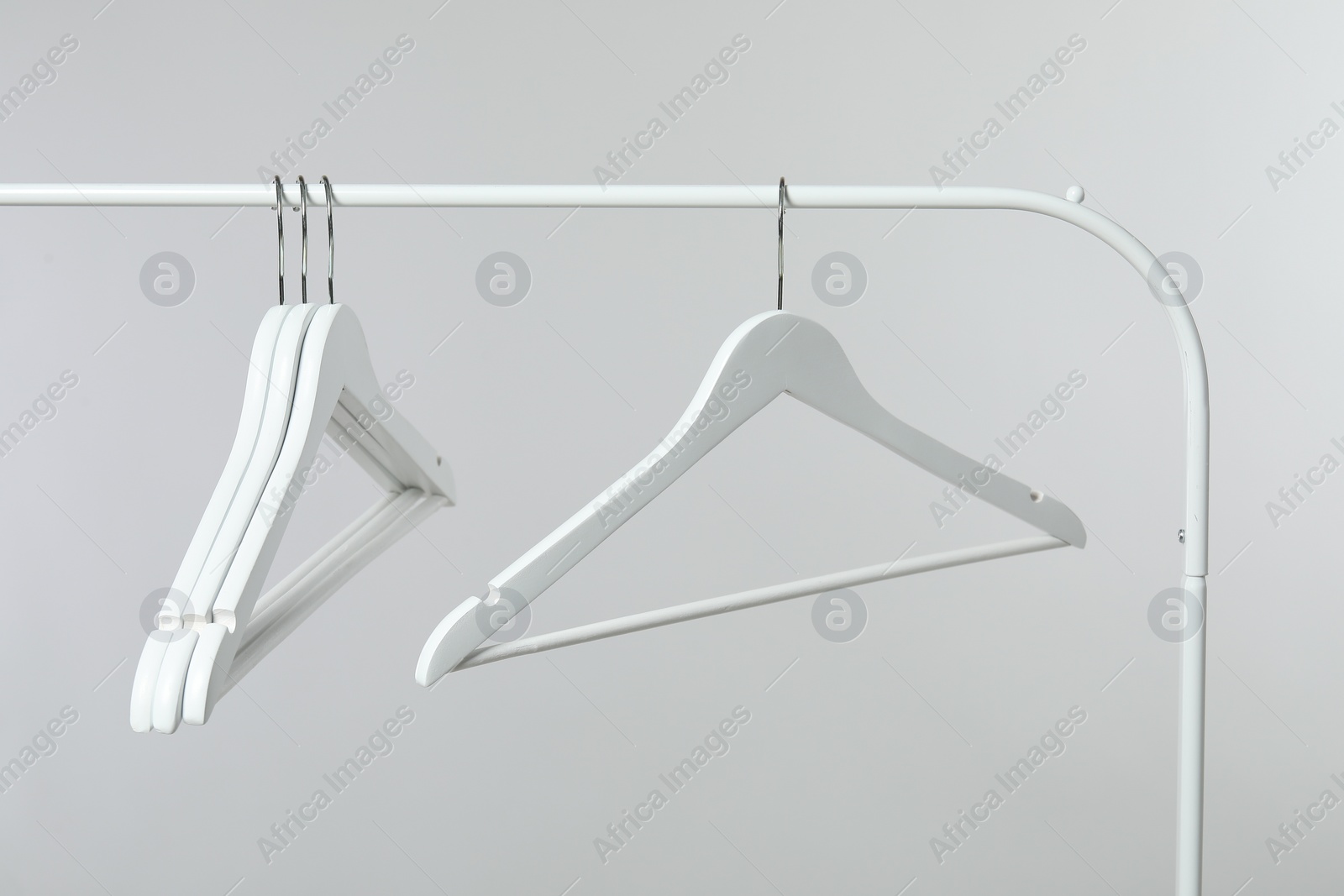 Photo of Empty clothes hangers on rack against light grey background