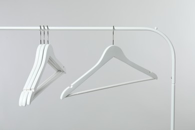 Photo of Empty clothes hangers on rack against light grey background