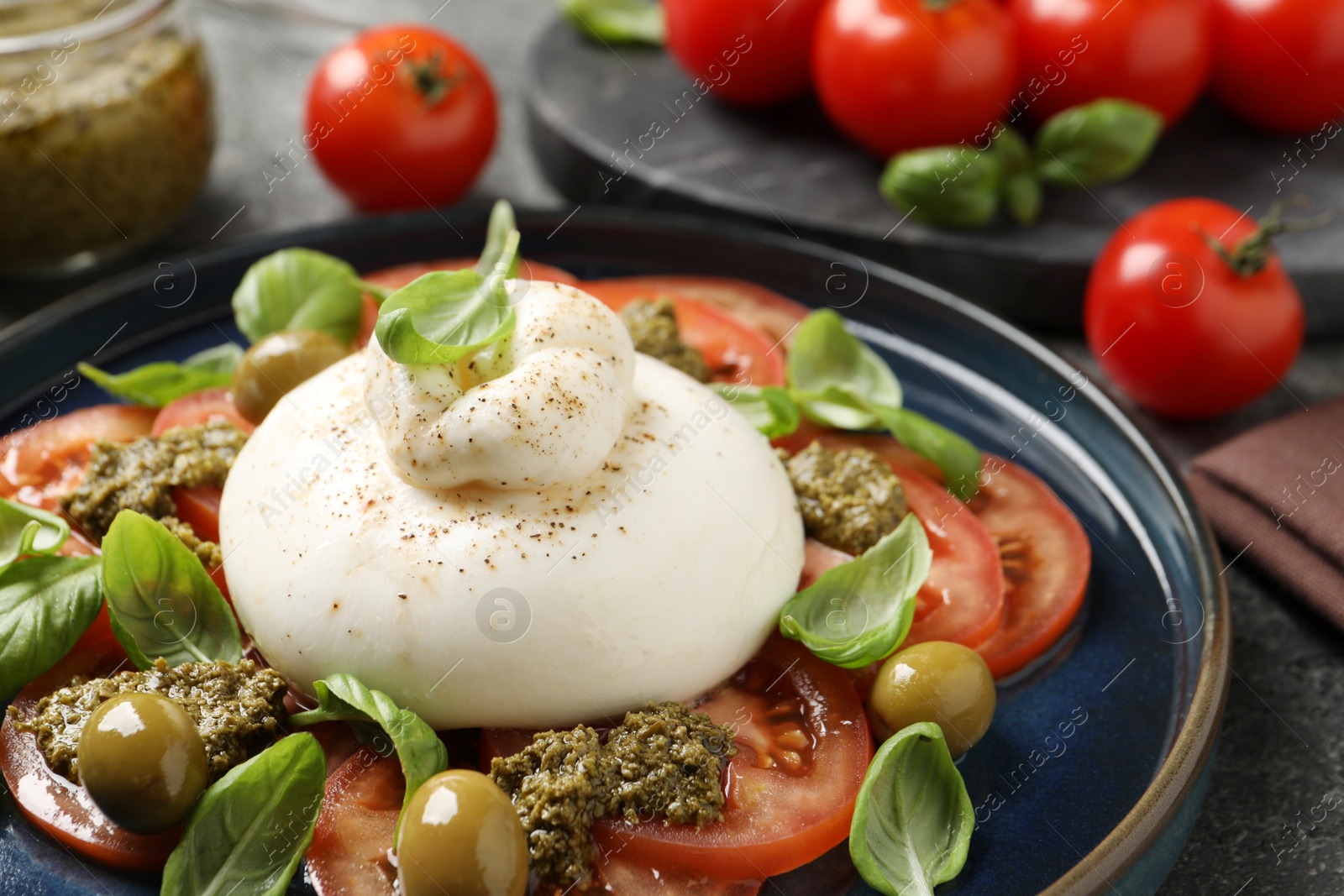 Photo of Delicious burrata salad served on grey table, closeup