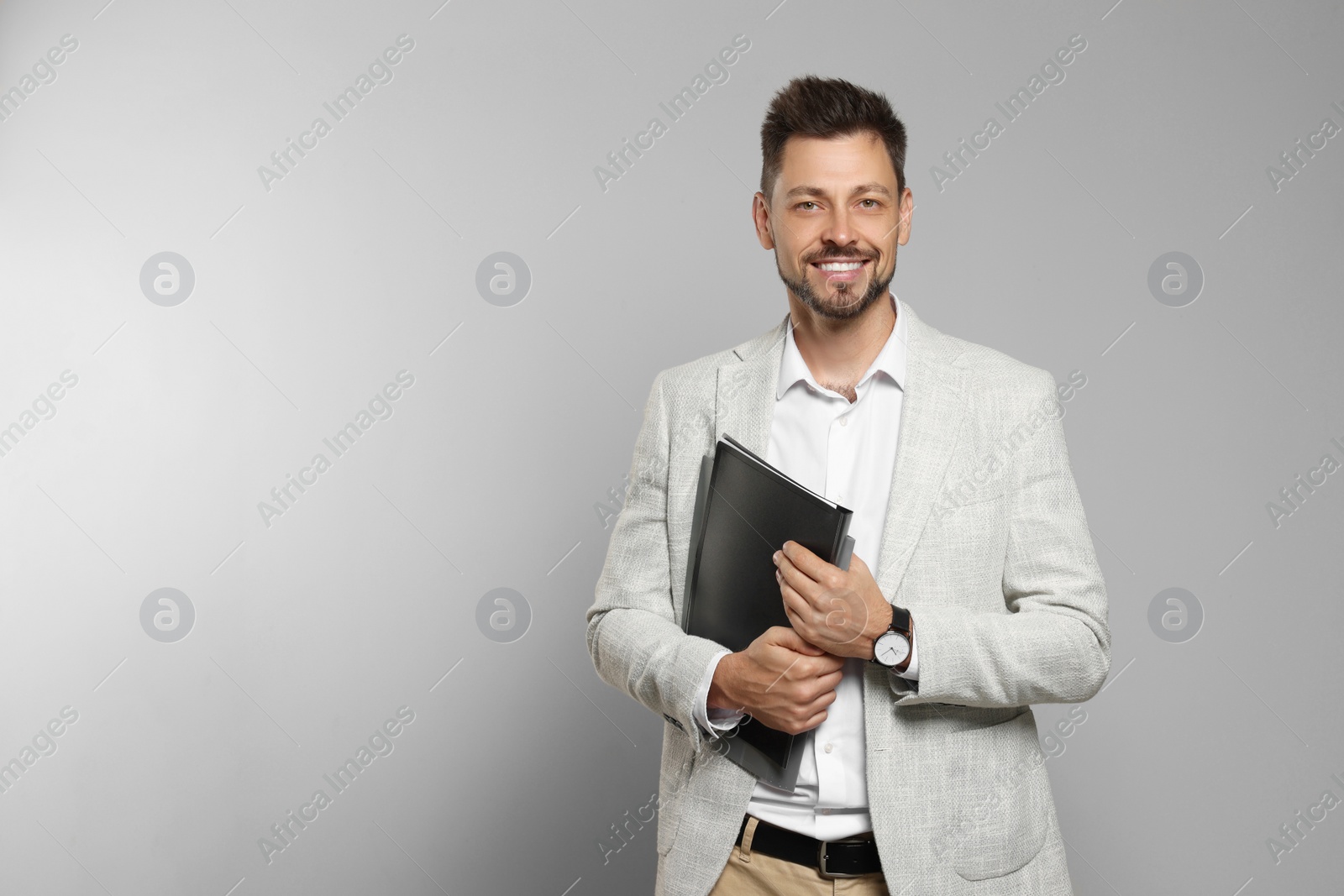 Photo of Happy teacher with stationery against beige background