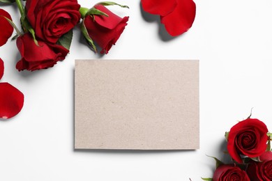 Blank card, beautiful red roses and petals on white background, flat lay. Space for text