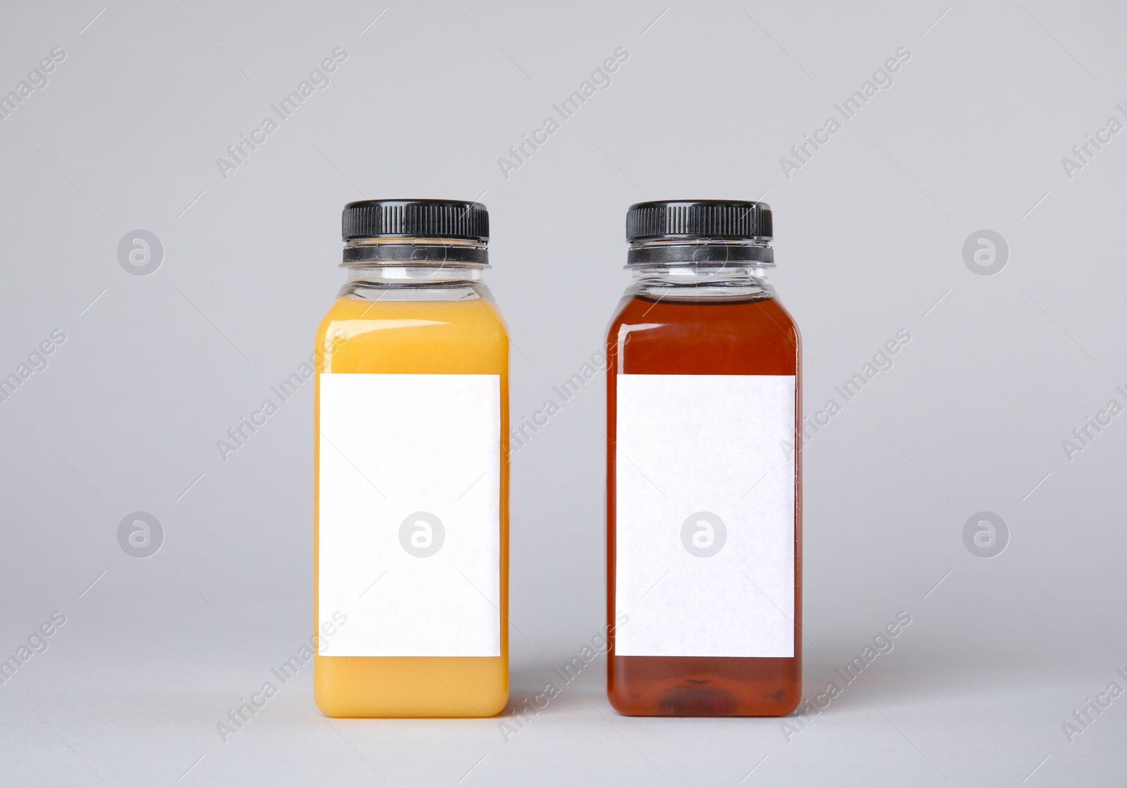 Photo of Tasty drinks in bottles with blank labels on color background. Mock up for design