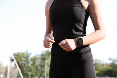 Photo of Woman with fitness tracker running outdoors, closeup