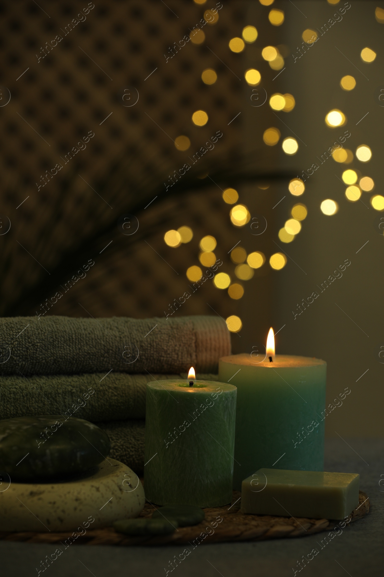 Photo of Spa composition. Burning candles, stones, soap and towels on table