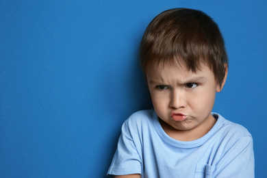 Photo of Portrait of emotional little boy on blue background