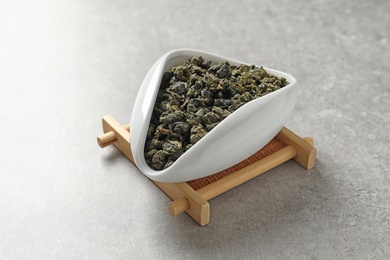 Photo of Chahe of Tie Guan Yin oolong tea leaves on grey background