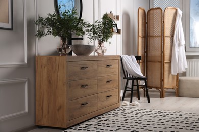 Photo of Modern bathroom interior with stylish mirror, eucalyptus branches, vessel sink and wooden vanity