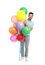Young man holding bunch of colorful balloons on white background