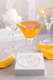 Photo of Tasty cocktails in glasses and orange slices on gray table, closeup