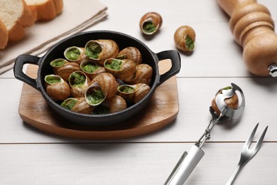 Photo of Delicious cooked snails served on white wooden table