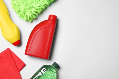 Bottles, cloth and car wash mitt on white background, flat lay. Space for text