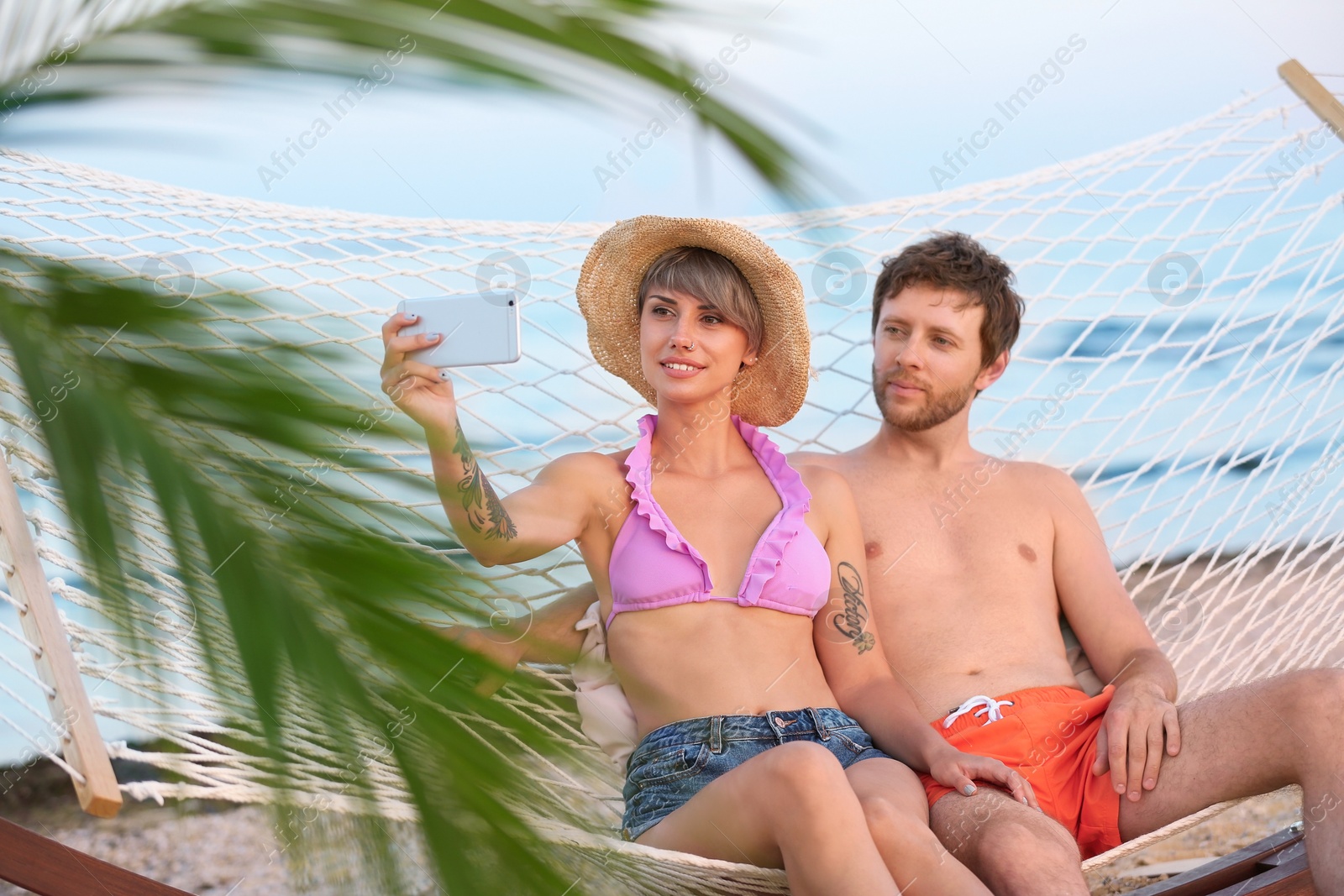 Photo of Young couple taking selfie in hammock on beach