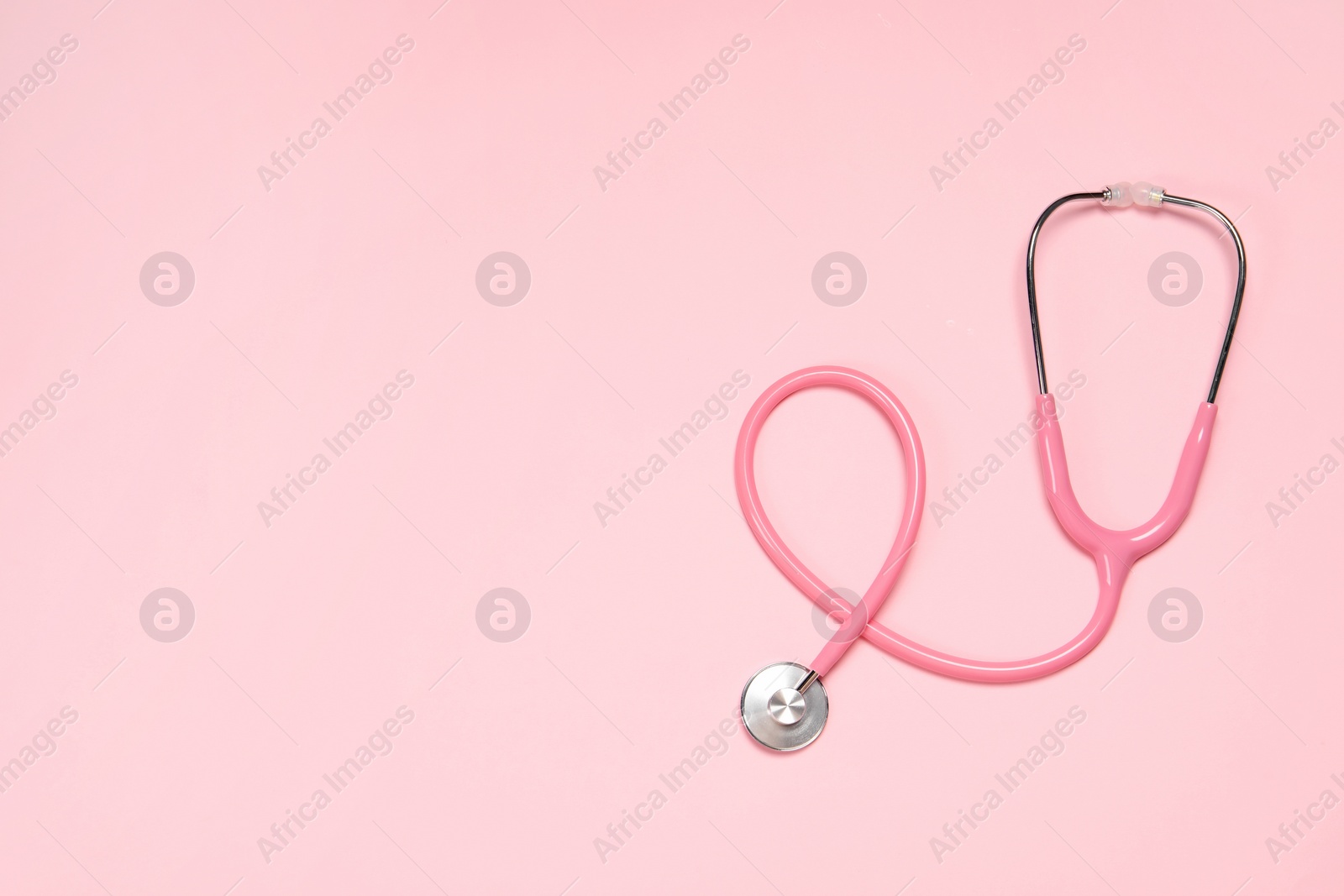 Photo of Stethoscope on pink background, top view. Space for text