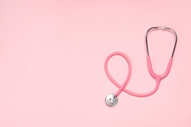 Photo of Stethoscope on pink background, top view. Space for text