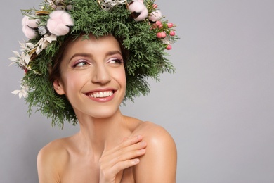 Photo of Happy young woman wearing wreath on grey background. Space for text