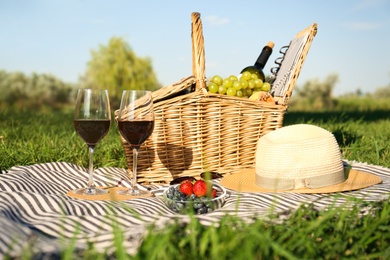 Photo of Red wine and different products for summer picnic served on blanket outdoors