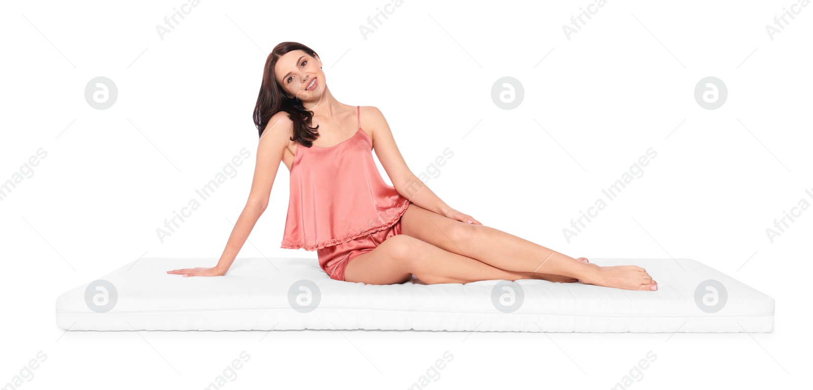 Photo of Young woman sitting on soft mattress against white background