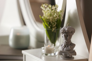 Beautiful David bust candle and flowers on table indoors, space for text
