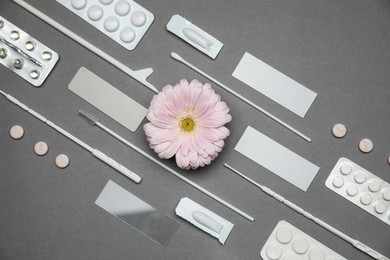 Photo of Many gynecological tools, pills and gerbera flower on grey background, flat lay