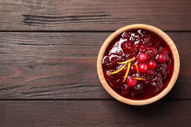 Photo of Cranberry sauce with orange peel on wooden table, top view. Space for text