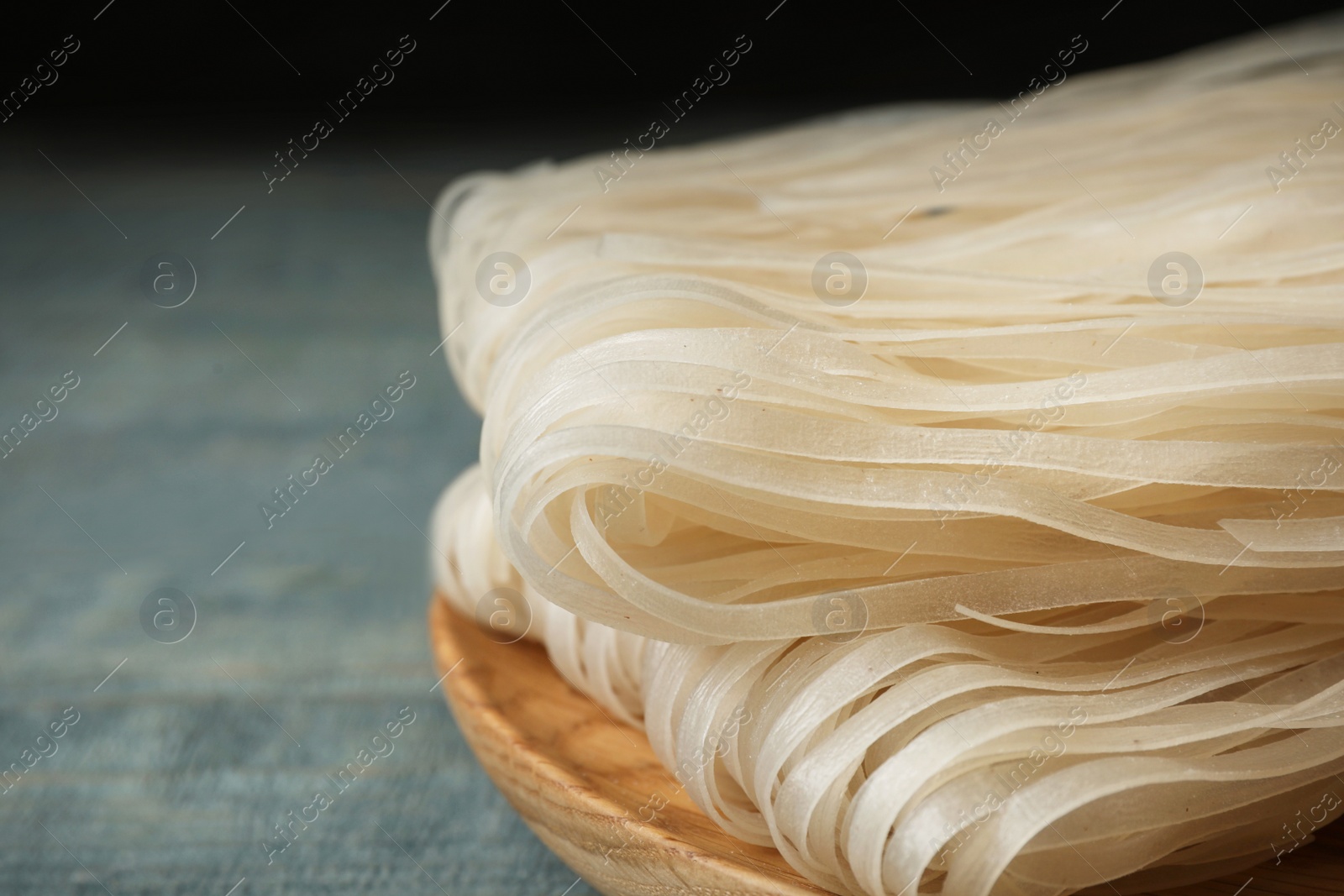 Photo of Plate with raw rice noodles on wooden table, closeup. Space for text